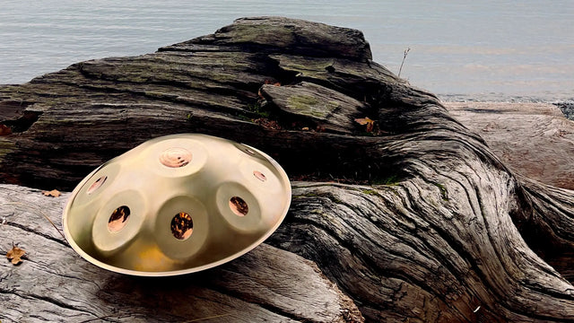 A golden handpan made by Handpanuni shines on the shore