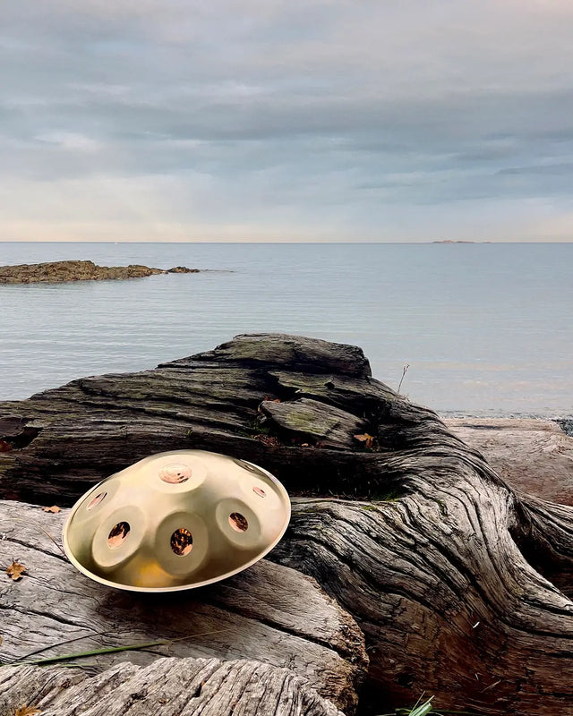 A golden handpan made by Handpanuni shines on the shore